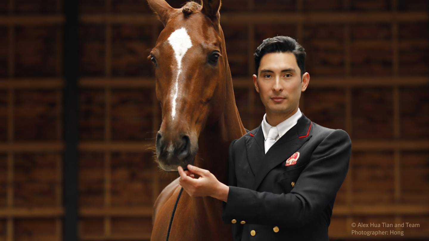 Alex Hua Tian stands next to his horse in a stable