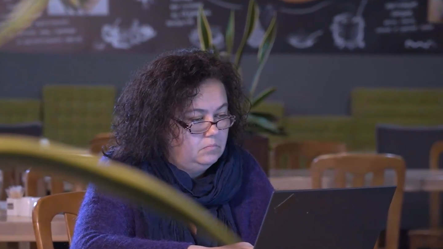 Eine mittelalte Frau sitzt in unserem Büro in Kiew vor ihrem Laptop.